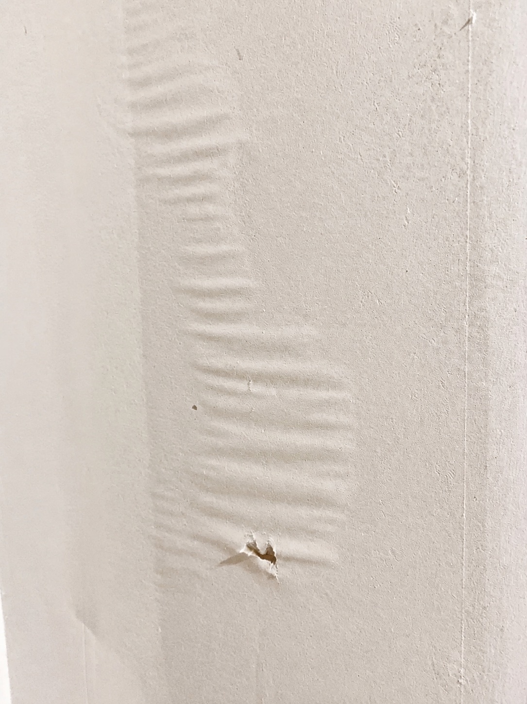 Torn drywall paper bubbling under a thin coat of joint compound