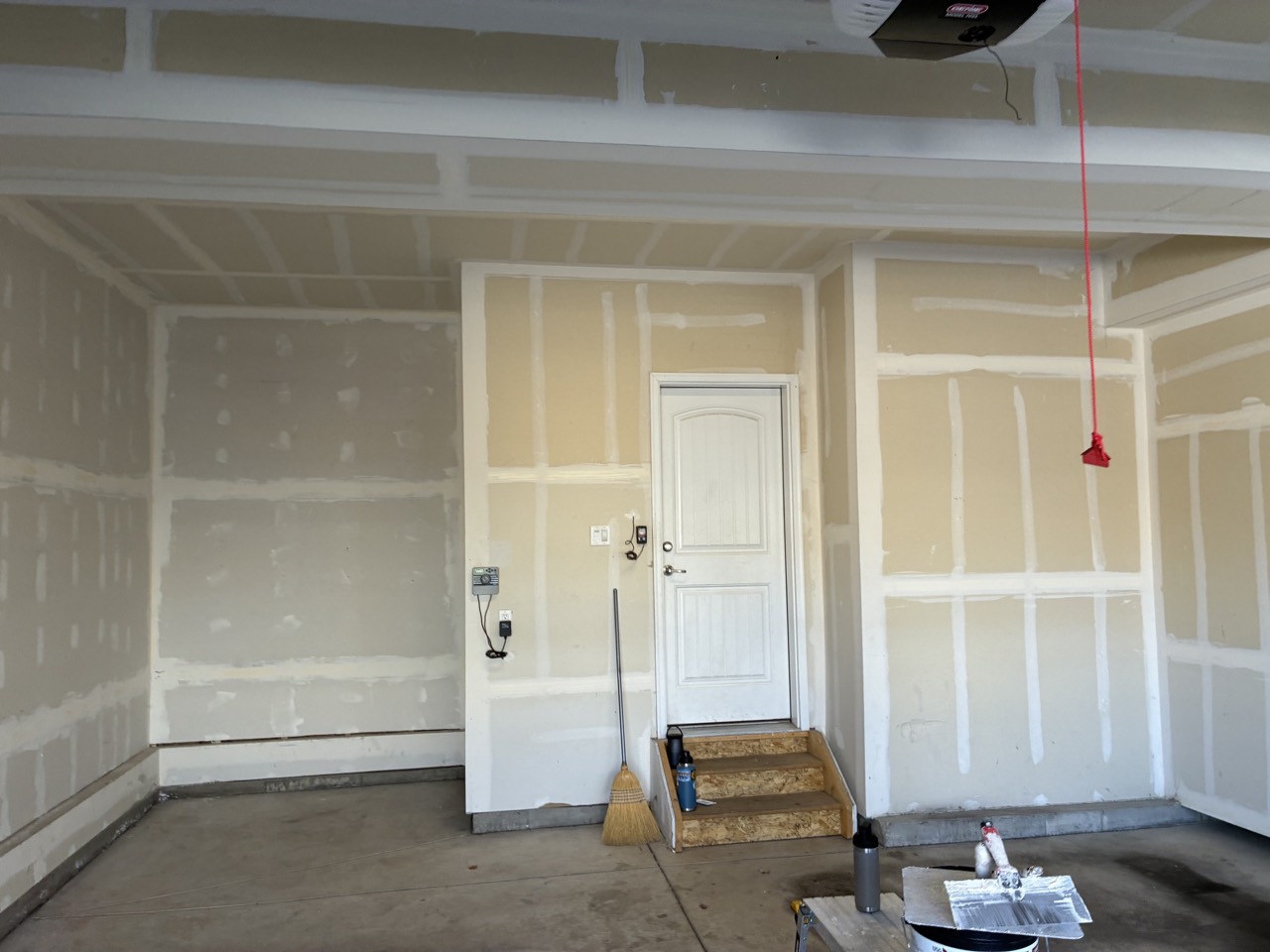 Garage entry wall showing coated drywall seams and unfinished concrete slab during the project