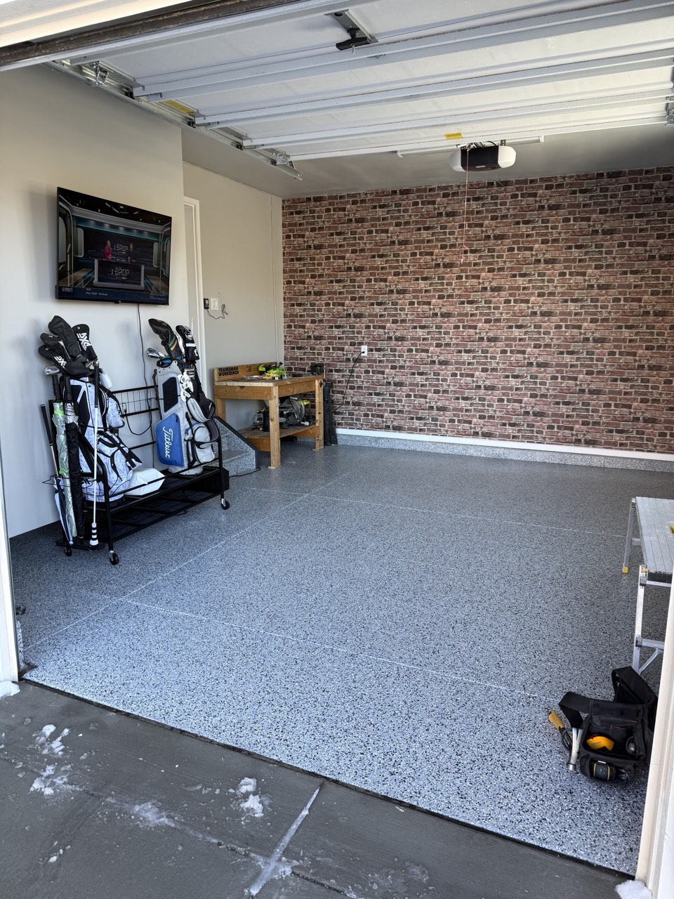 Completed garage interior with epoxy floor, painted drywall, and organized storage